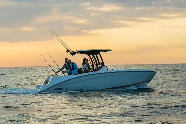 Slide: The Image of 2024 Yamaha Boats 255 FSH Sport H cruising at sunset with fishing rods. - 2