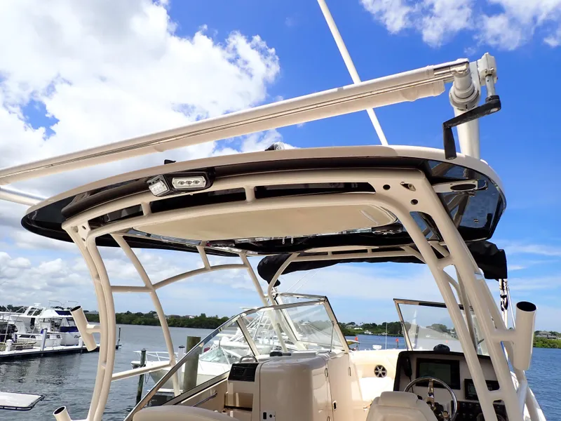 Slide: The Image of 2019 Grady-White Freedom 275 boat docked, showcasing helm and hardtop under blue sky. - 18