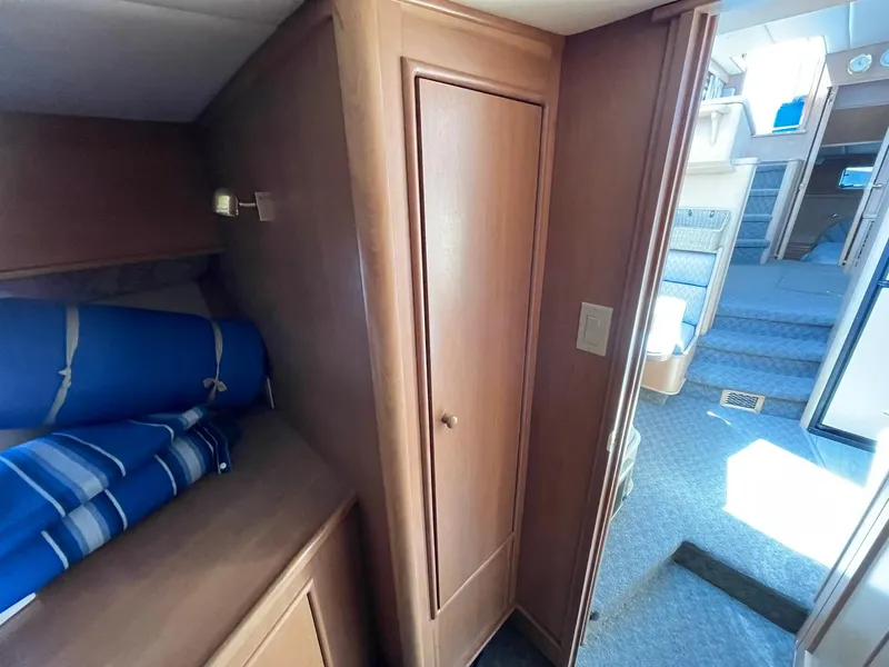 Slide: The Image of 1994 Queenship Motor Yacht interior with wooden cabinetry and blue bedding. - 18