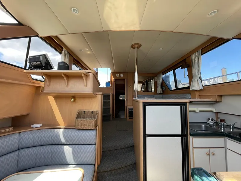 Slide: The Image of Interior of a 1994 Queenship Motor Yacht with seating, kitchenette, and natural light. - 2