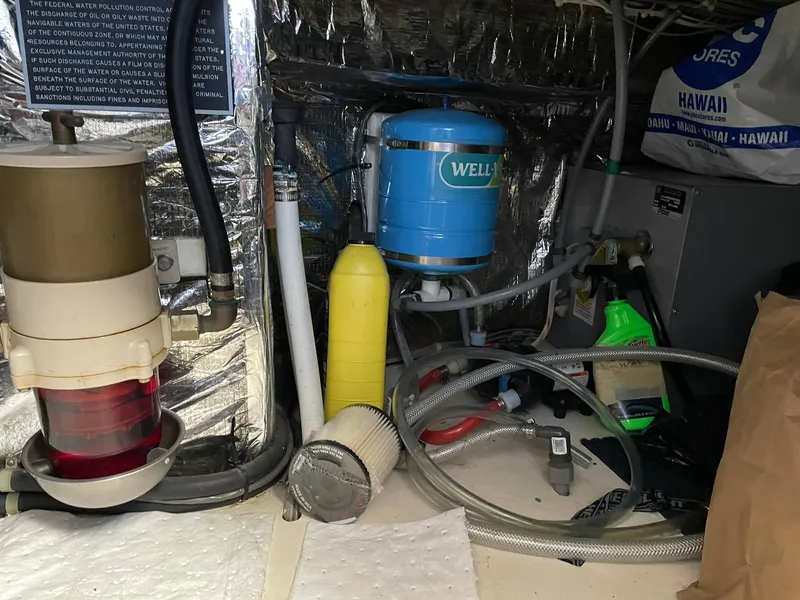 Slide: The Image of Engine room of a 1994 Queenship Motor Yacht with various equipment and hoses. - 25