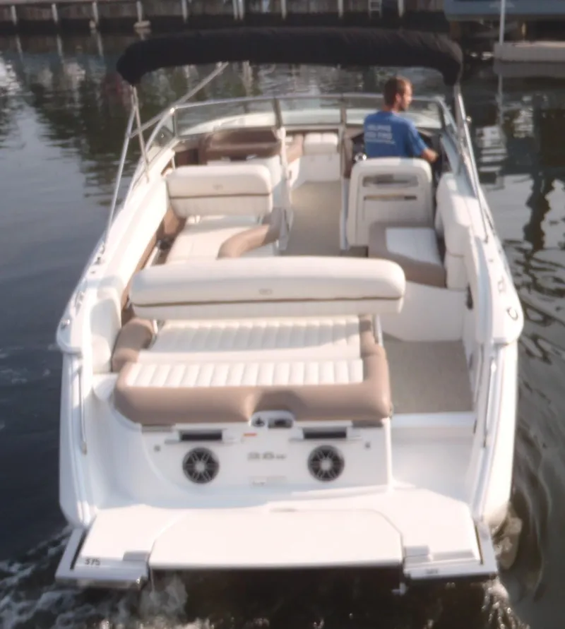 Slide: The Image of 2013 Cobalt 26SD boat on water, rear view, with seating and a person at the helm. - 10