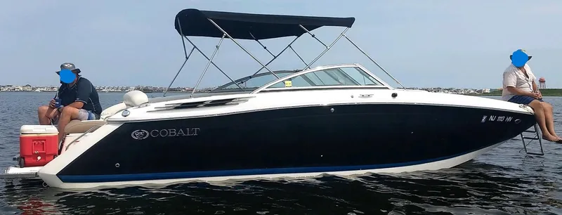 Slide: The Image of 2013 Cobalt 26SD boat with canopy on calm water, two people seated at the back. - 19