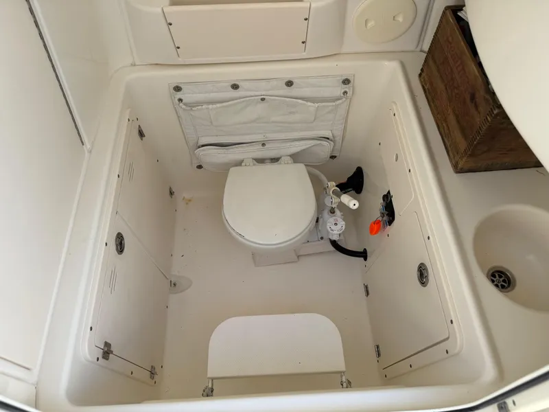 Slide: The Image of 2007 Boston Whaler 270 Outrage boat bathroom with toilet and storage compartments. - 27