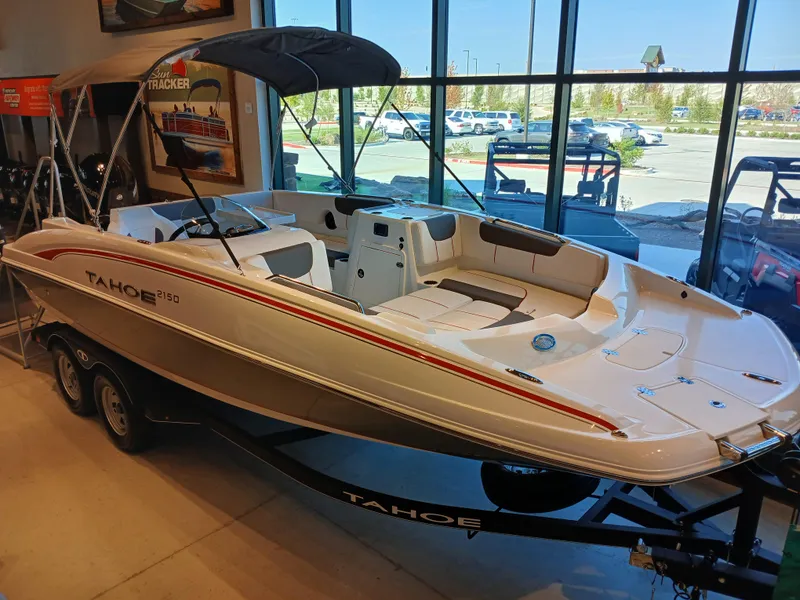 The Image of 2024 Tahoe 2150 boat displayed indoors with trailer and canopy. - 0