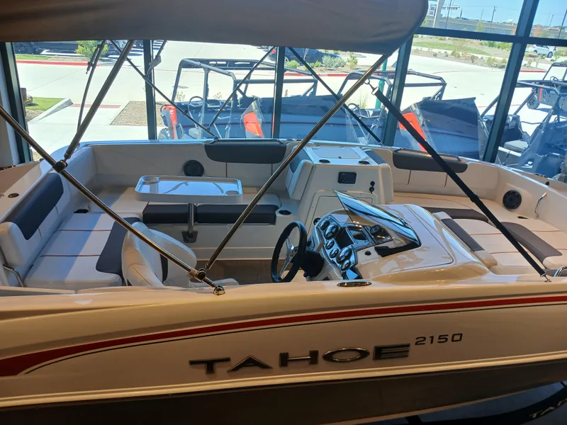 Slide: The Image of 2024 Tahoe 2150 boat interior with seating and steering wheel in showroom. - 1