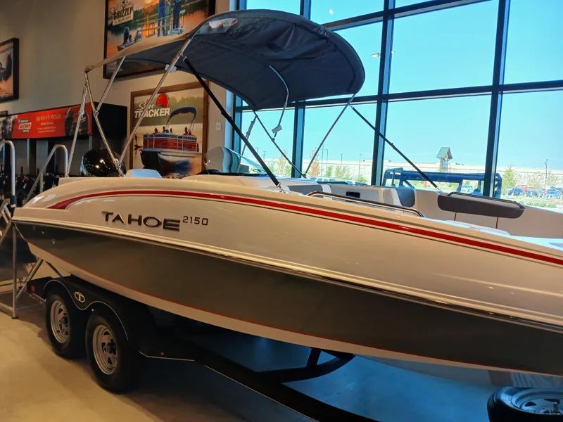 Slide: The Image of 2024 Tahoe 2150 boat displayed indoors with a canopy and trailer. - 3