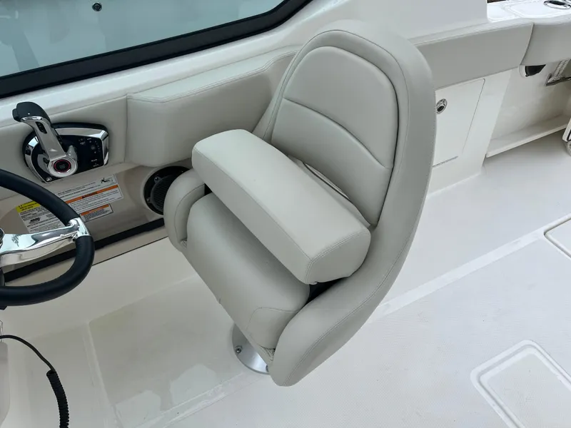 Slide: The Image of 2025 Boston Whaler 240 Vantage helm seat with armrest and steering wheel detail. - 15