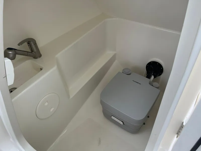 Slide: The Image of Interior of 2025 Boston Whaler 240 Vantage boat, featuring compact bathroom amenities. - 23