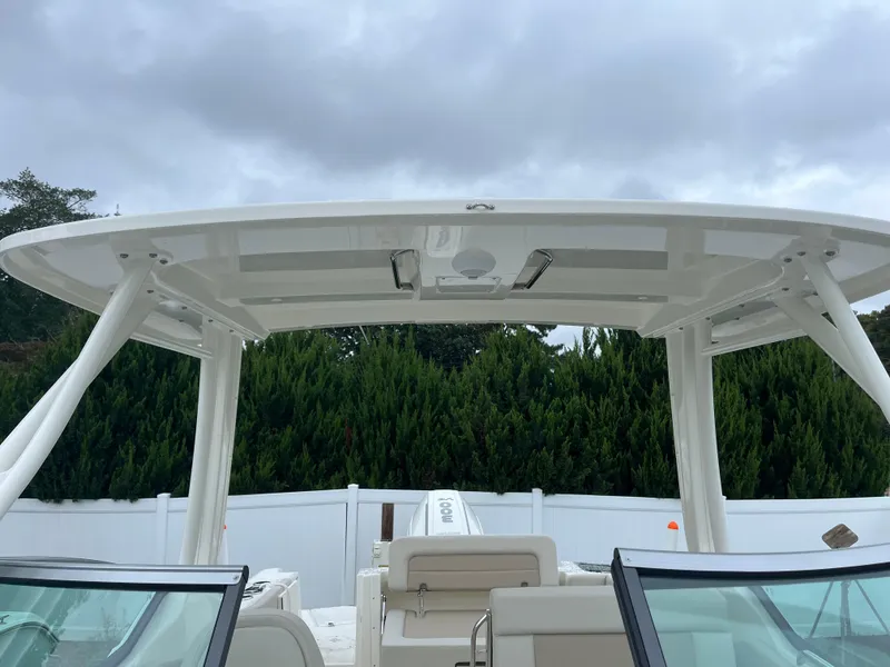 Slide: The Image of Boston Whaler 240 Vantage 2025 boat with T-top, viewed from the deck, against cloudy sky. - 27