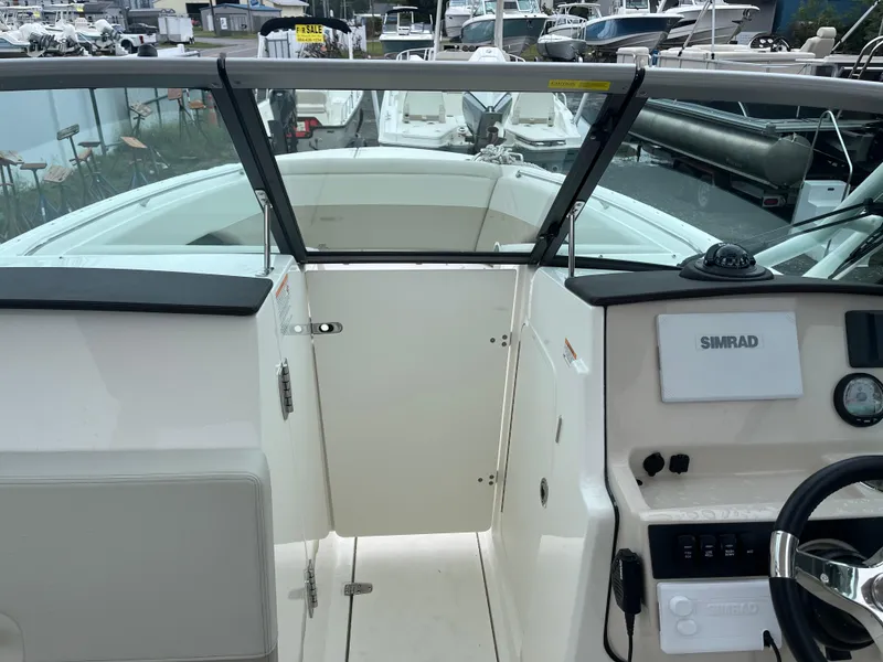 Slide: The Image of 2025 Boston Whaler 240 Vantage boat interior with Simrad navigation system, docked among other boats. - 28
