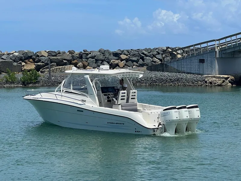 Slide: The Image of 2008 Hydra-Sports 3500VX boat cruising near a rocky shoreline and bridge. - 13