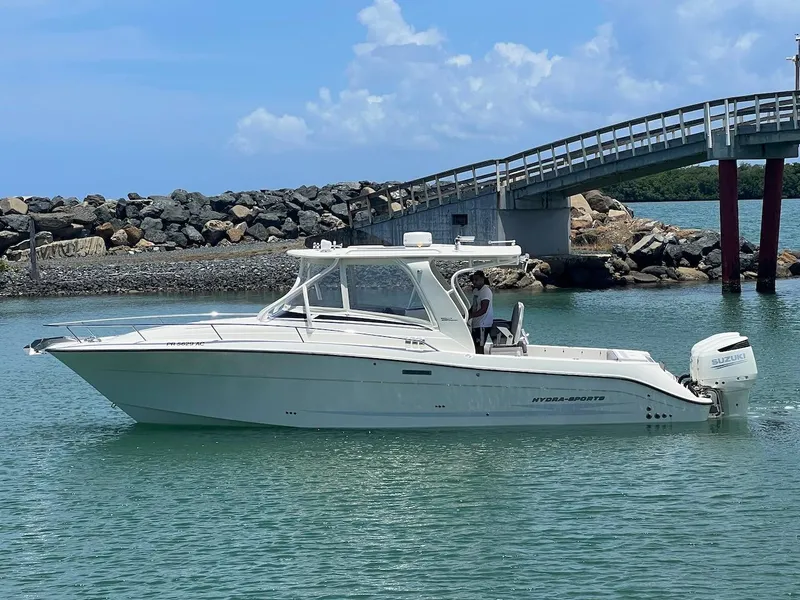 Slide: The Image of 2008 Hydra-Sports 3500VX boat cruising near a rocky shoreline and bridge. - 2