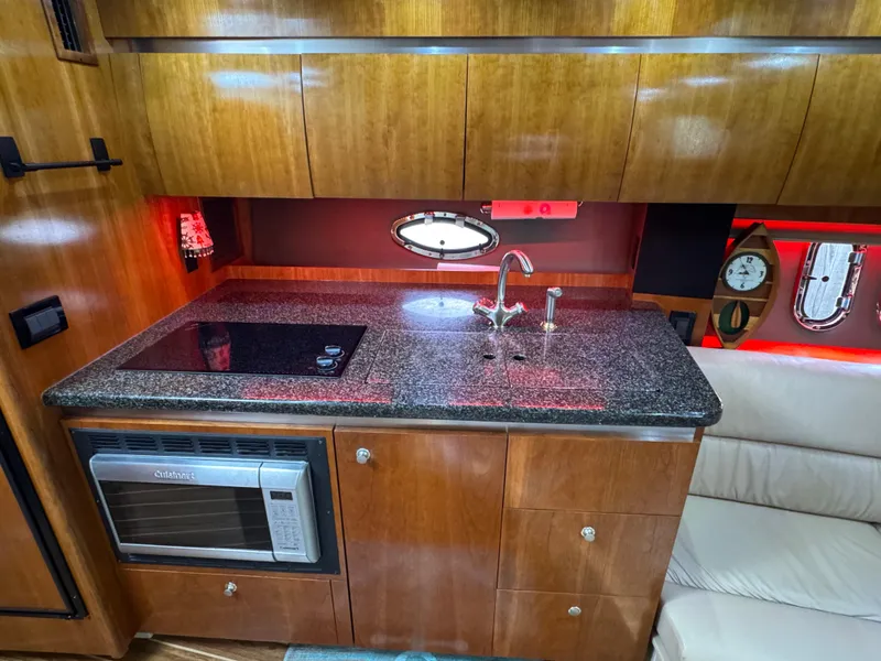 Slide: The Image of 2006 Cruisers Yachts 420 Express galley with granite countertop, microwave, and modern fixtures. - 23