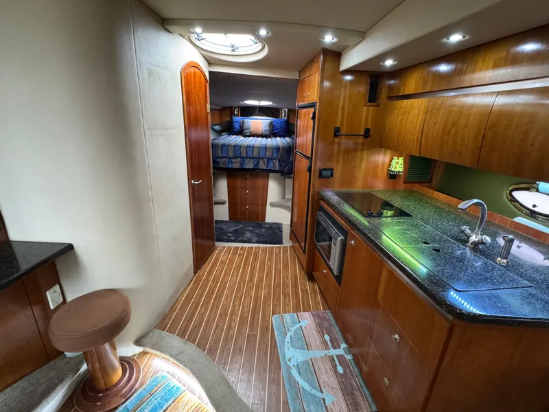 Slide: The Image of 2006 Cruisers Yachts 420 Express interior with kitchen, wood flooring, and cozy bedroom. - 25