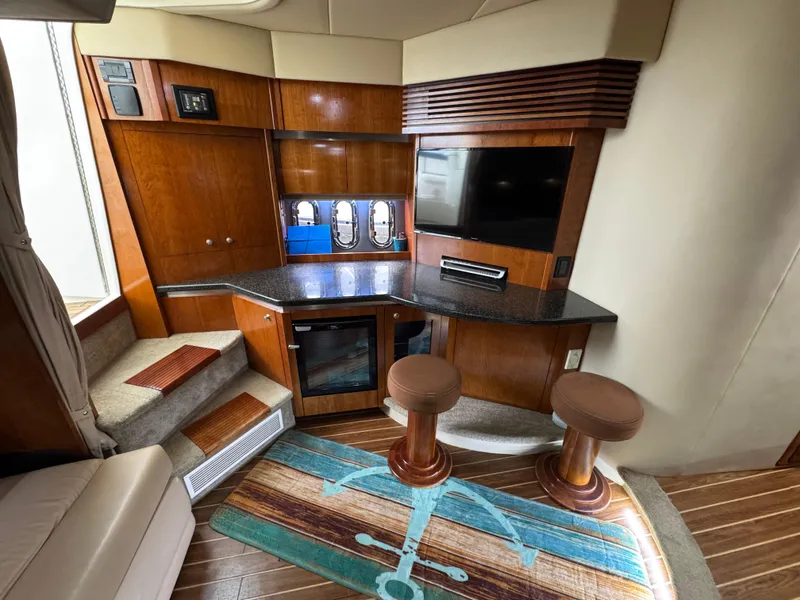 Slide: The Image of Interior of 2006 Cruisers Yachts 420 Express with wood cabinetry, bar stools, and entertainment area. - 26