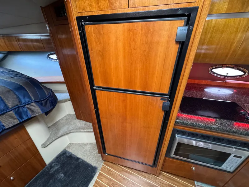 Slide: The Image of 2006 Cruisers Yachts 420 Express interior with wood cabinetry, fridge, and kitchenette. - 30