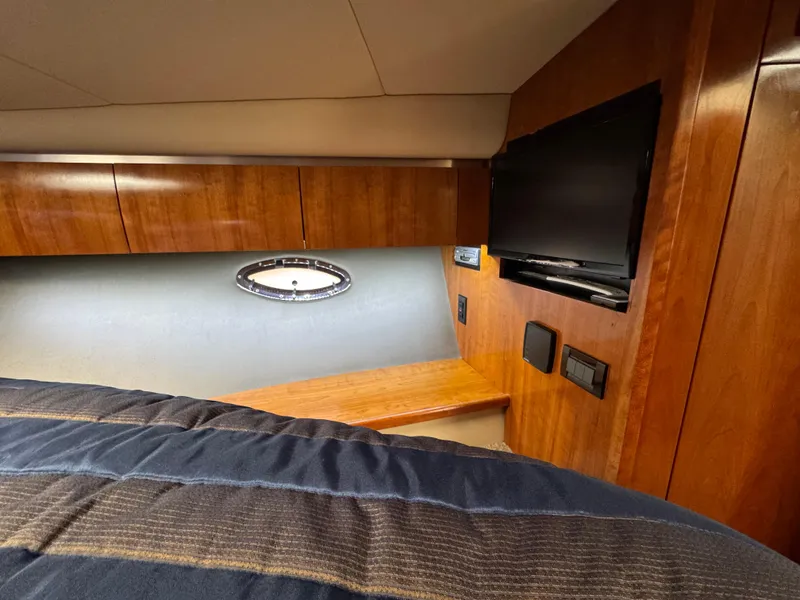 Slide: The Image of 2006 Cruisers Yachts 420 Express cabin with wood paneling and a mounted TV. - 35