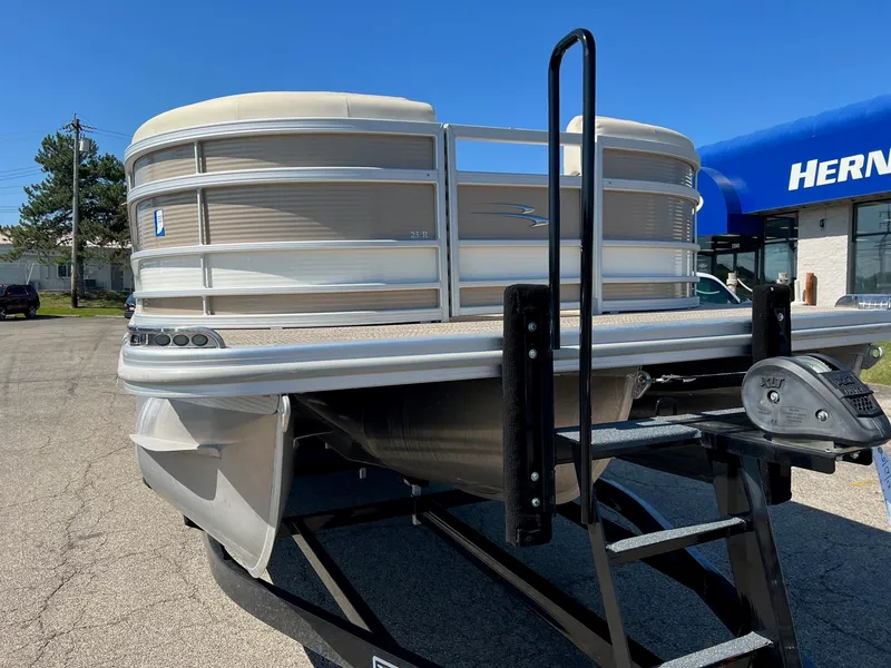 Slide: The Image of 2020 Bennington R 25 RSB pontoon boat on a trailer in a dealership lot. - 1