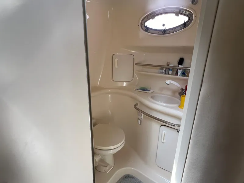 Slide: The Image of 1998 Sea Ray 330 Sundancer bathroom with toilet, sink, and porthole window. - 16