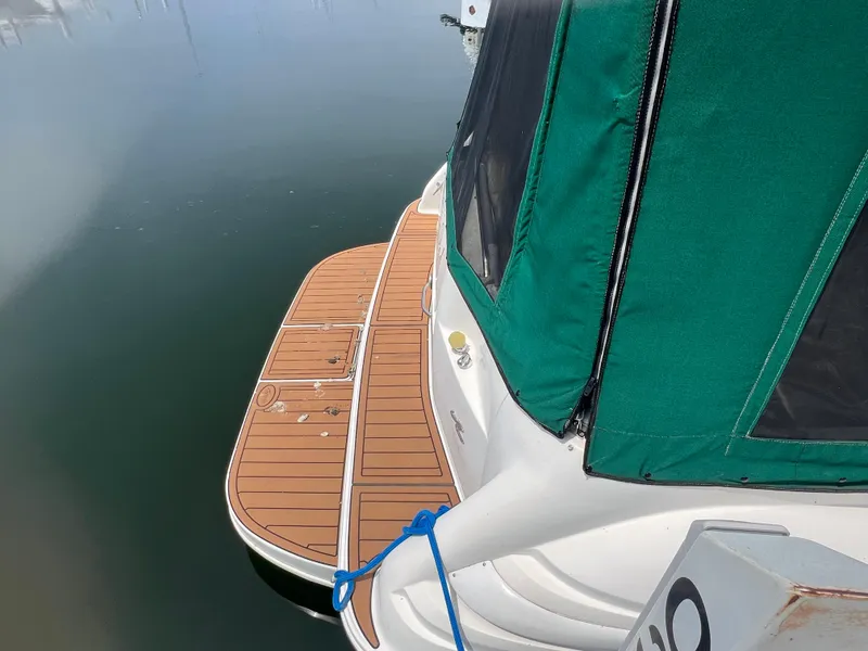 Slide: The Image of 1998 Sea Ray 330 Sundancer with green canvas cover and wooden swim platform. - 3