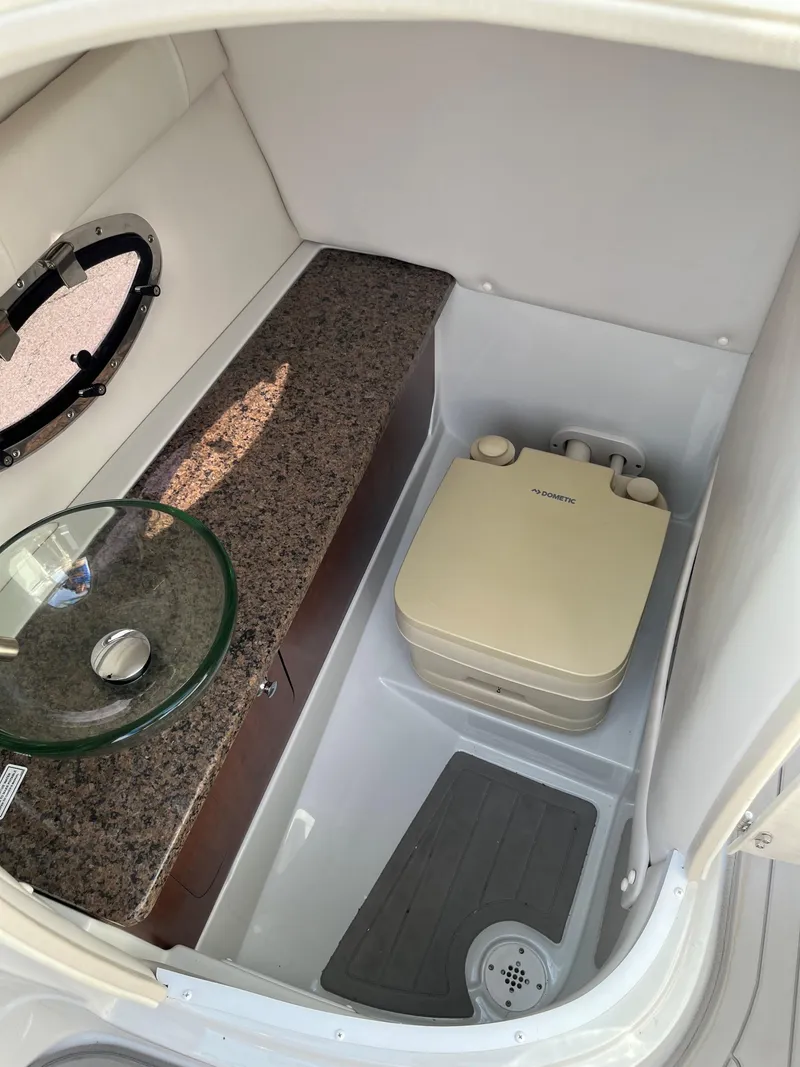 Slide: The Image of 2019 Crownline 265 SS SURF boat interior with compact bathroom and portable toilet. - 11