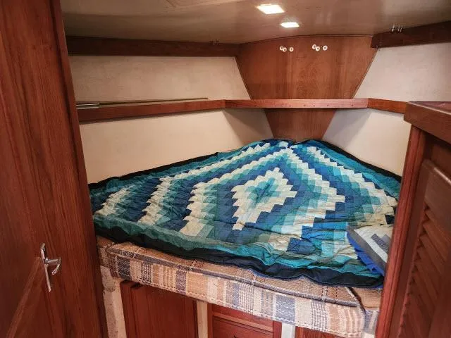 Slide: The Image of 1985 Catalina 36 sailboat cabin with cozy bed and blue quilt. - 18