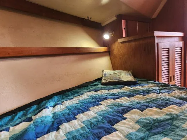 Slide: The Image of Cozy cabin bed in a 1985 Catalina 36 sailboat with a blue quilt. - 20