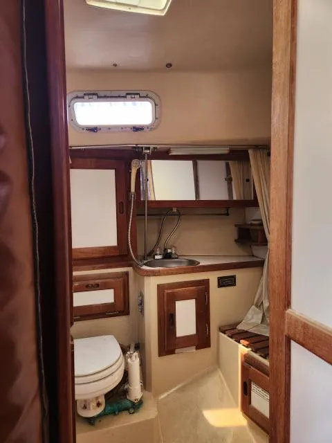 Slide: The Image of 1985 Catalina 36 sailboat bathroom with sink, toilet, and wooden cabinetry. - 22