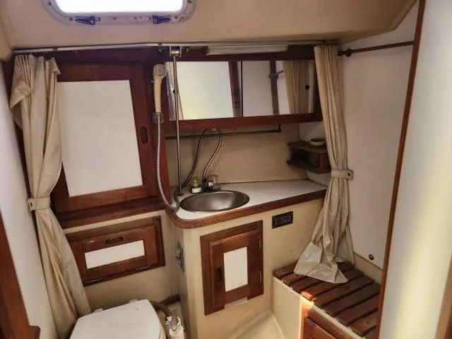 Slide: The Image of 1985 Catalina 36 sailboat bathroom with sink, mirror, and wooden cabinetry. - 23