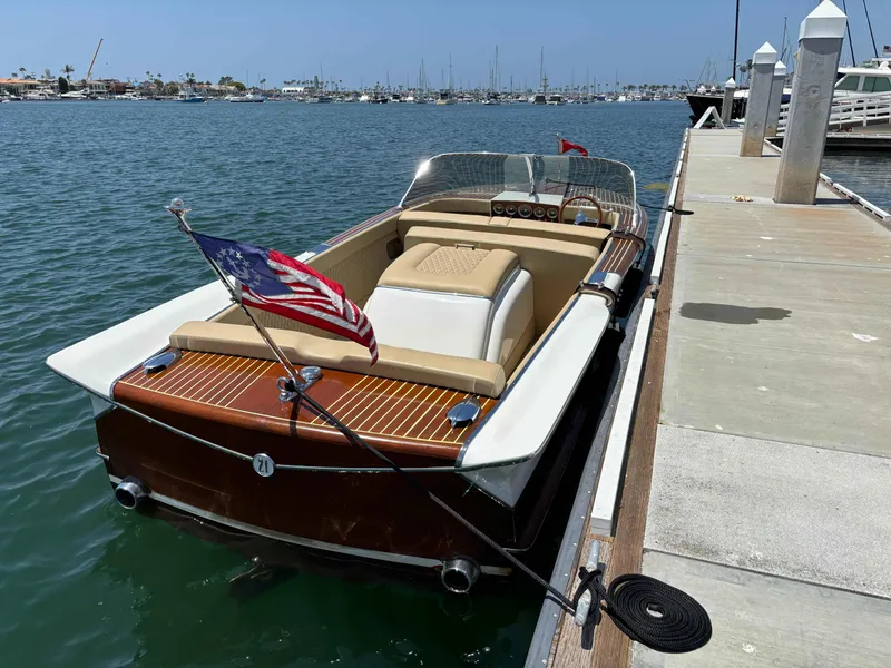 Slide: The Image of 1960 Chris-Craft Continental Gull Wing boat docked, featuring classic wooden design and American flag. - 1