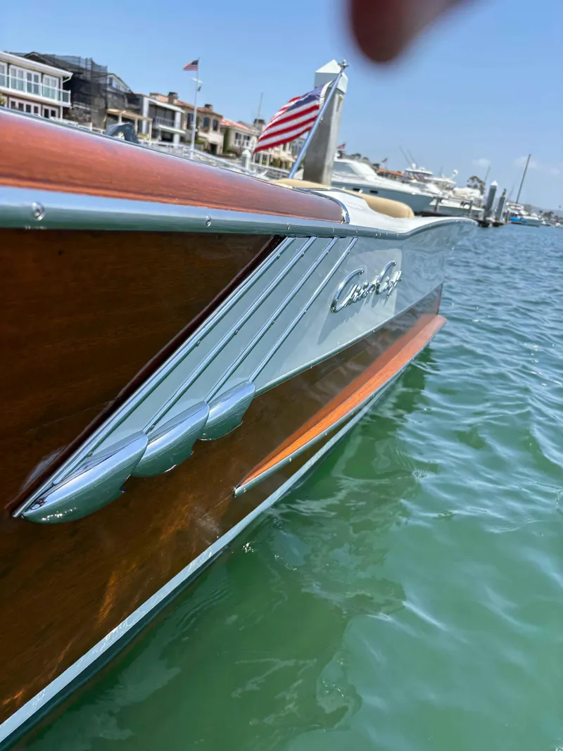 Slide: The Image of 1960 Chris-Craft Continental Gull Wing boat on water, showcasing sleek wooden design and American flag. - 4