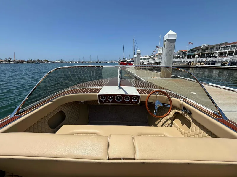 Slide: The Image of 1960 Chris-Craft Continental Gull Wing boat at dock, featuring classic wooden dashboard and steering wheel. - 8