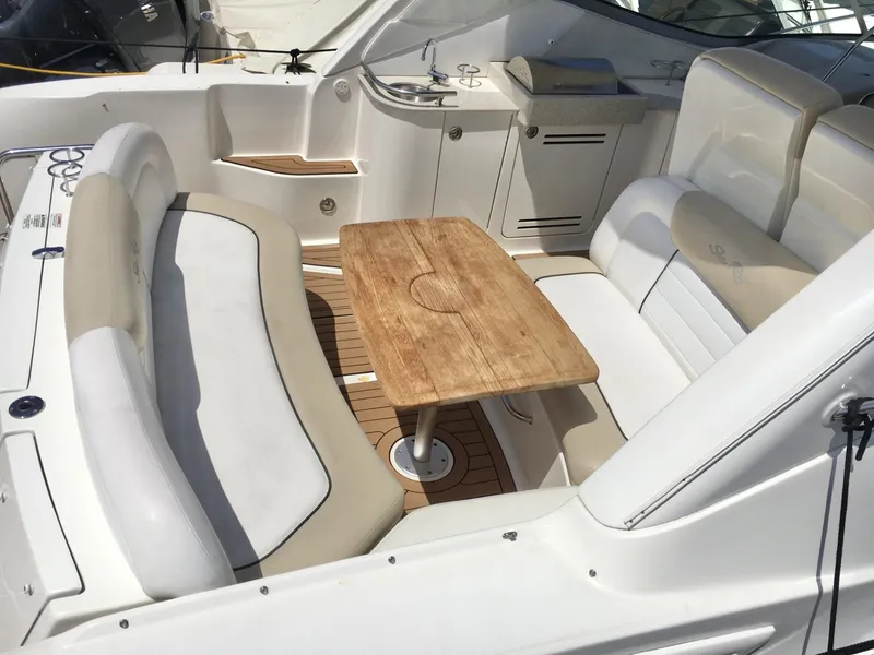 Slide: The Image of 2010 Sea Ray 330 Sundancer cockpit with seating and wooden table. - 17