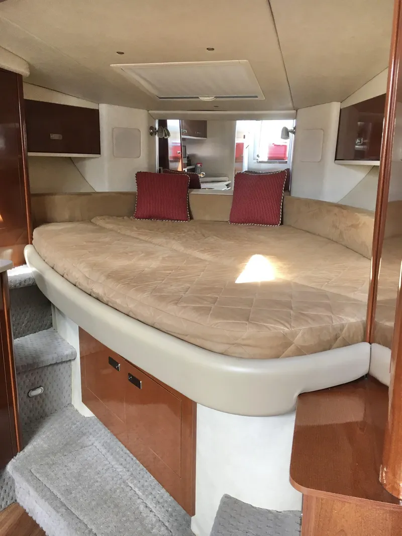 Slide: The Image of 2010 Sea Ray 330 Sundancer cabin with cozy bed and red pillows. - 24