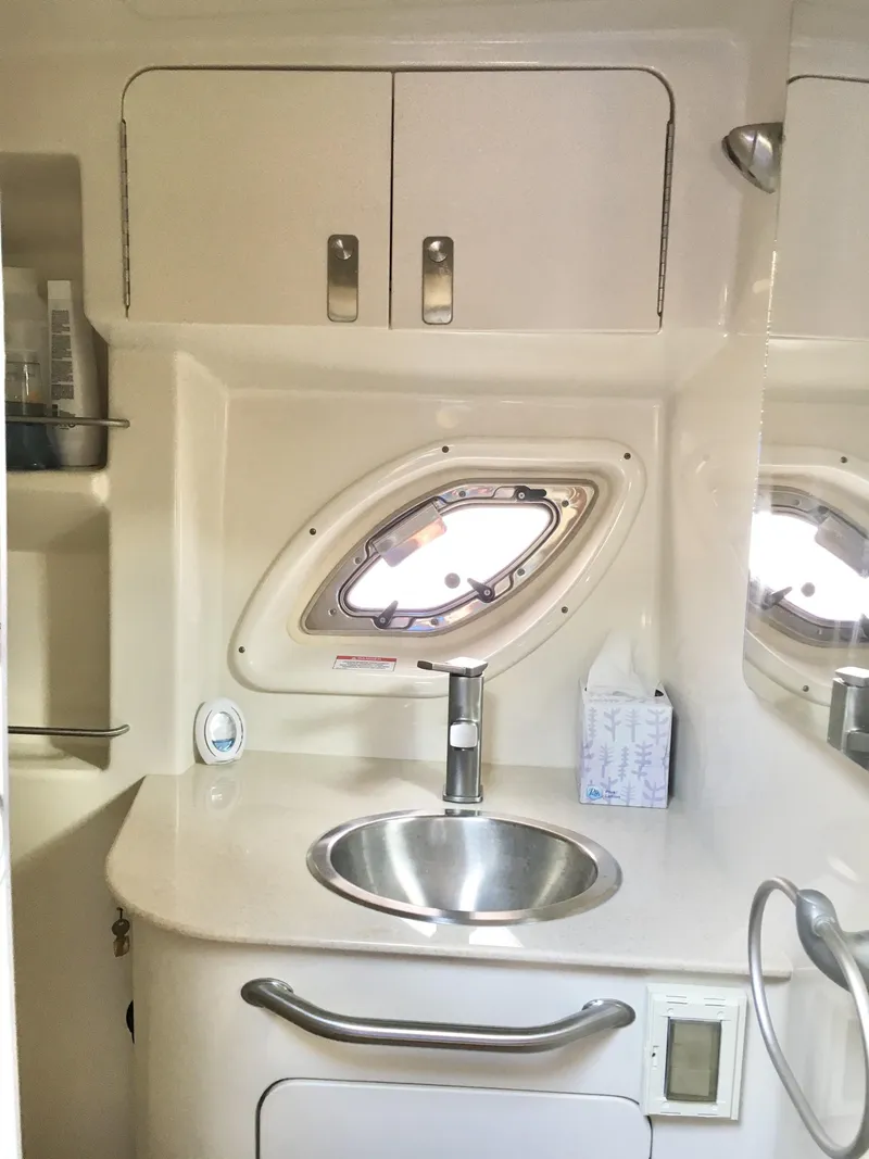 Slide: The Image of 2010 Sea Ray 330 Sundancer bathroom with sink, porthole, and storage cabinets. - 32
