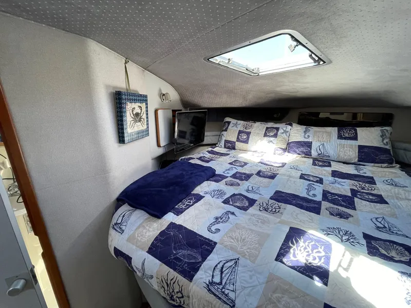 Slide: The Image of Cozy bedroom in 1989 Sea Ray 420 boat with nautical-themed bedding and skylight. - 12