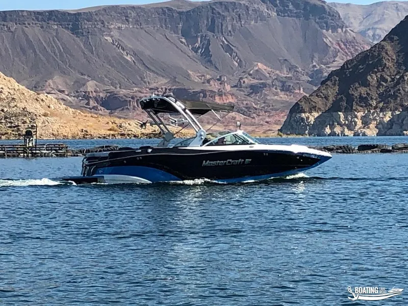 Slide: The Image of 2018 MasterCraft XT 22 boat cruising on a lake with mountainous background. - 14