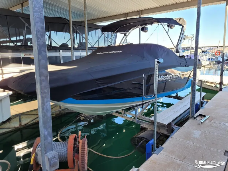 Slide: The Image of 2018 MasterCraft XT 22 boat docked with cover on, in a marina. - 16