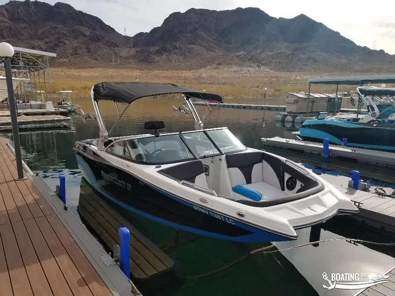 Slide: The Image of 2018 MasterCraft XT 22 boat docked at a marina with mountainous background. - 7