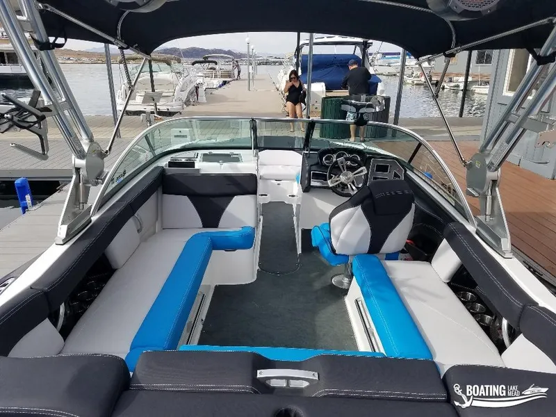 Slide: The Image of 2018 MasterCraft XT 22 boat interior at dock, featuring blue and white seating. - 9