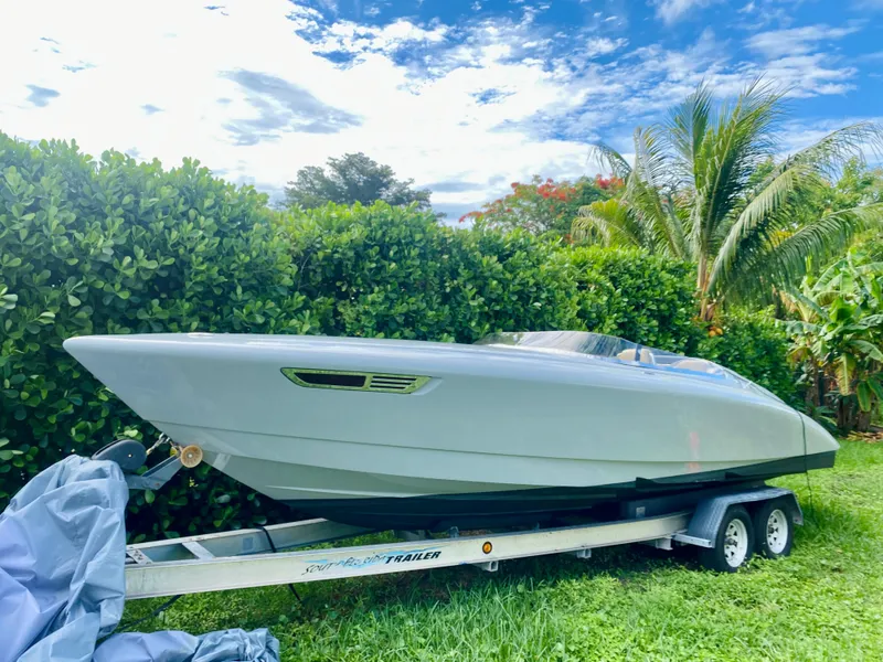 The Image of 2008 Porsche Fearless 28 speedboat on trailer, surrounded by lush greenery. - 1
