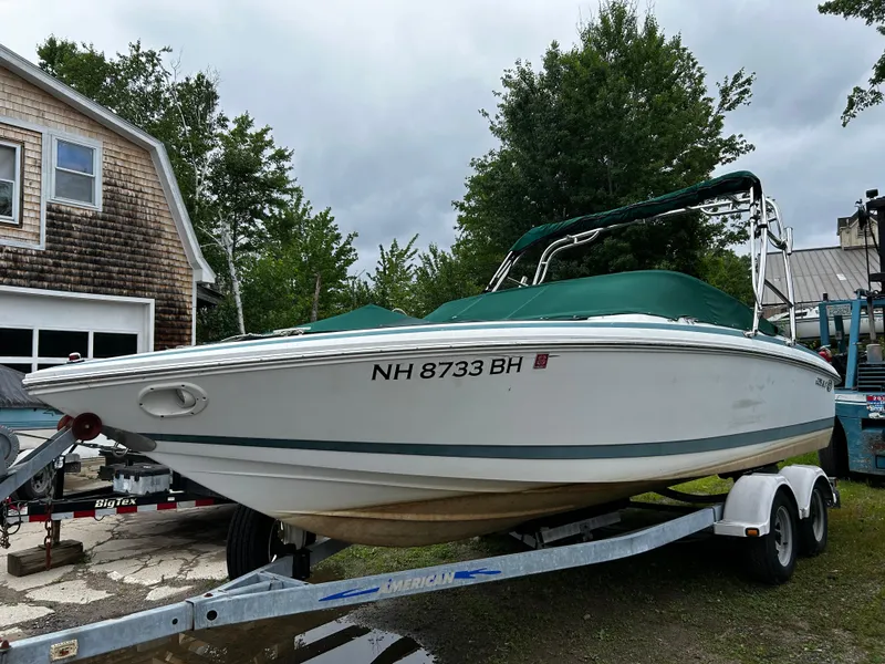 Slide: The Image of 2001 Cobalt 226 boat on trailer with green cover, parked outdoors. - 2