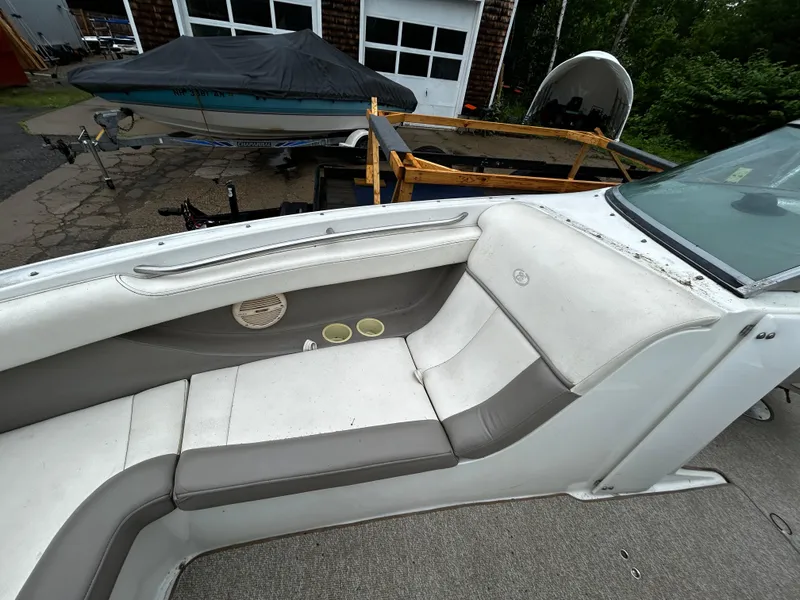 Slide: The Image of 2001 Cobalt 226 boat interior with white and gray seating, cup holders, and a covered boat in the background. - 35