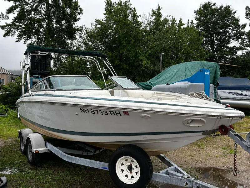Slide: The Image of 2001 Cobalt 226 boat on a trailer, parked outdoors near trees and other covered boats. - 4