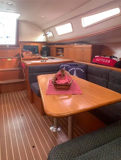 Slide: The Image of 2004 Hunter 33 sailboat interior with wood finish, dining area, and cozy seating. - 18