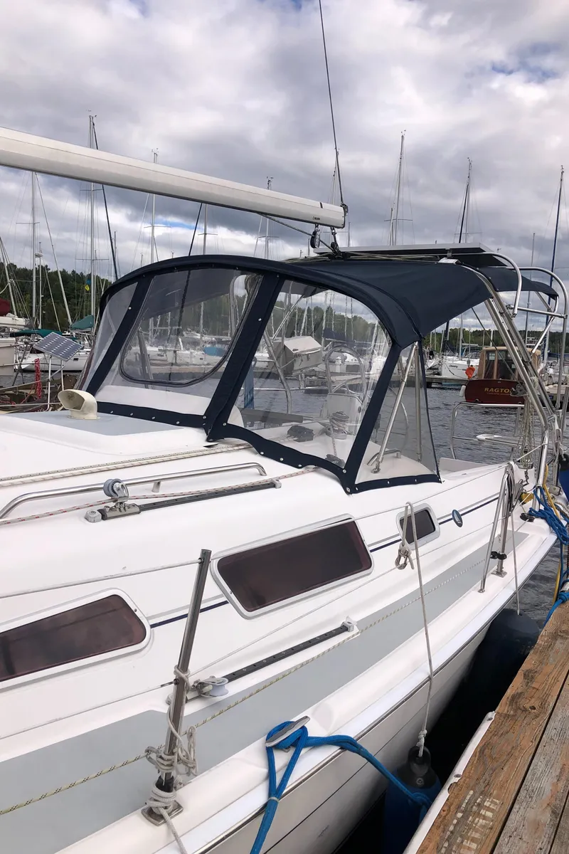 Slide: The Image of 2004 Hunter 33 sailboat docked at marina, featuring a blue canopy and sleek design. - 7
