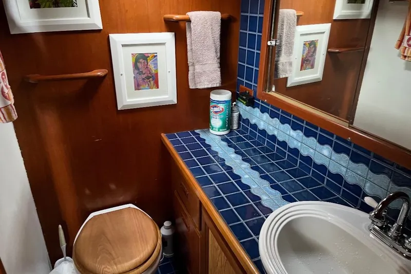 Slide: The Image of Wood-paneled boat bathroom with blue tiles, sink, and framed art, 1984 Custom 43 Steady Sailor. - 3