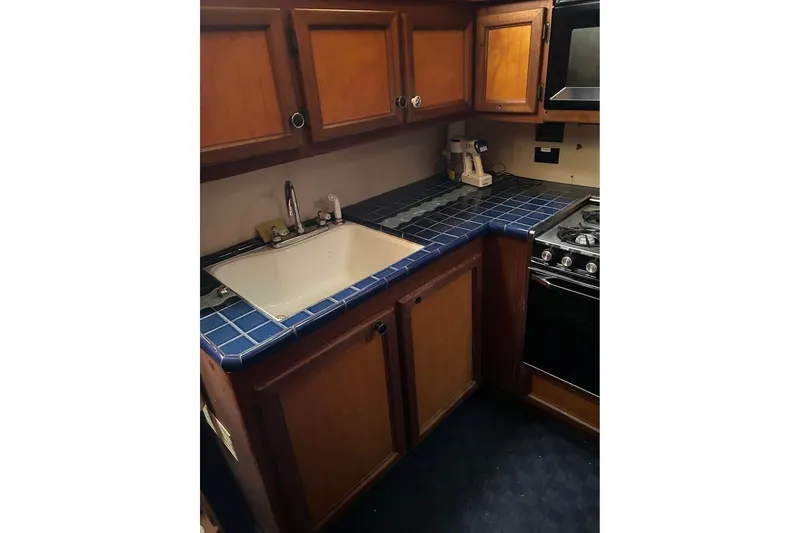 Slide: The Image of 1984 Custom 43 Steady Sailor kitchen with blue tile countertops and wooden cabinets. - 31