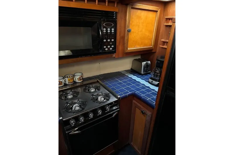Slide: The Image of Compact kitchen in 1984 Custom 43 Steady Sailor with stove, microwave, and blue-tiled countertop. - 34